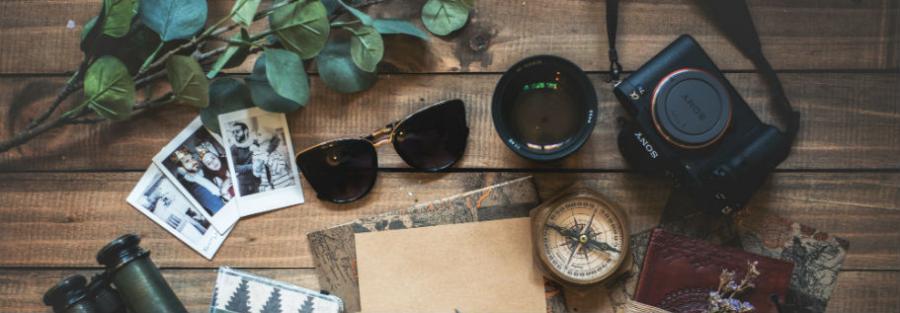 kompas, kort, solbriller og rejsedokumenter på et bord