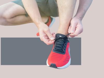 Person i sportstøj gør en løbesko klar ved at binde snørebånd.